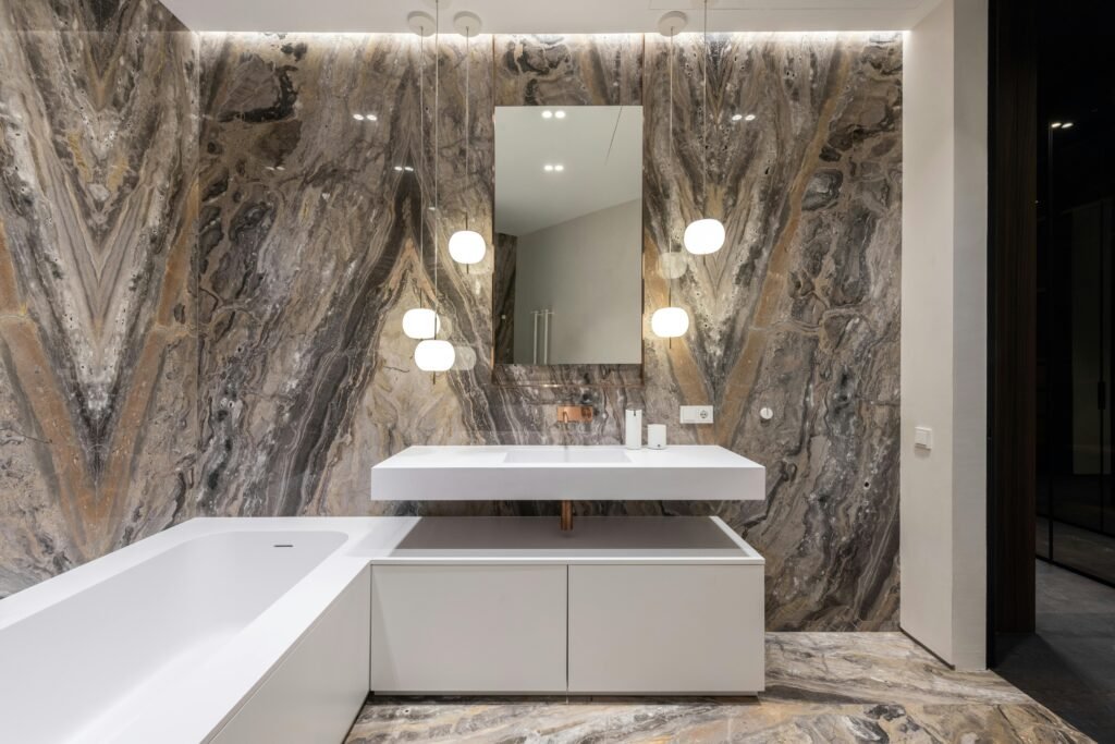 Elegant modern bathroom featuring marble walls, white fixtures, and stylish lighting.